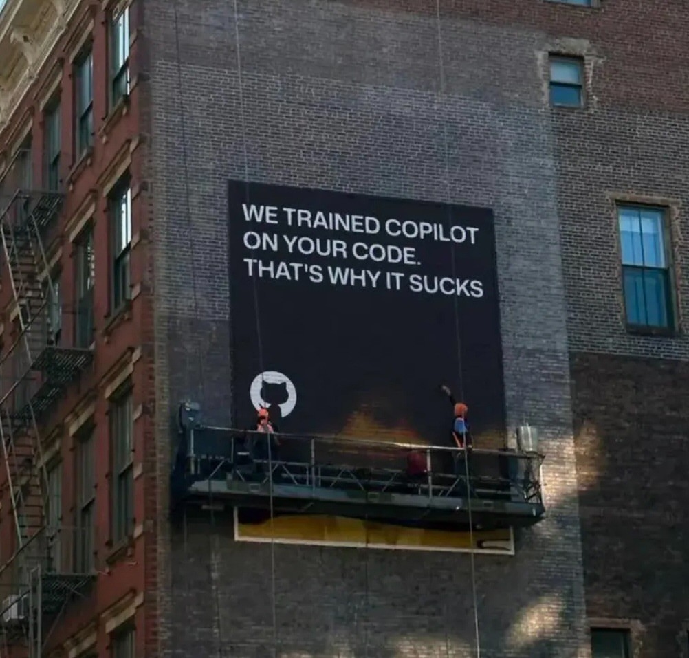 Photo d'une grande affiche en train d'être installée sur un pignon d'immeuble, et sur laquelle il est écrit "We trained Copilot on your code. That's why it sucks"